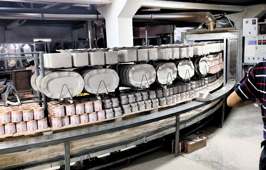 Ceramic biscuit ware stacked on kiln furniture during firing preparation in ceramic factory