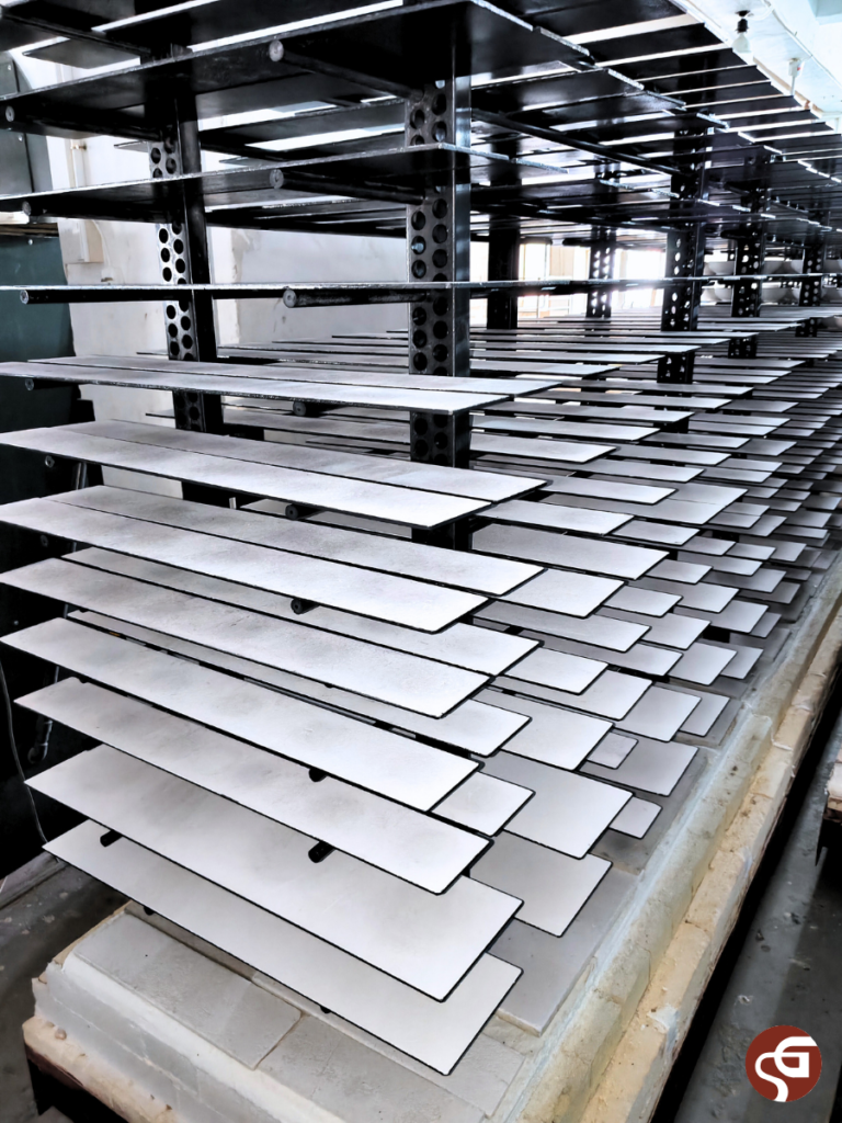 Kiln shelves loaded on a post-and-beam kiln furniture setup for ceramic firing in a factory.