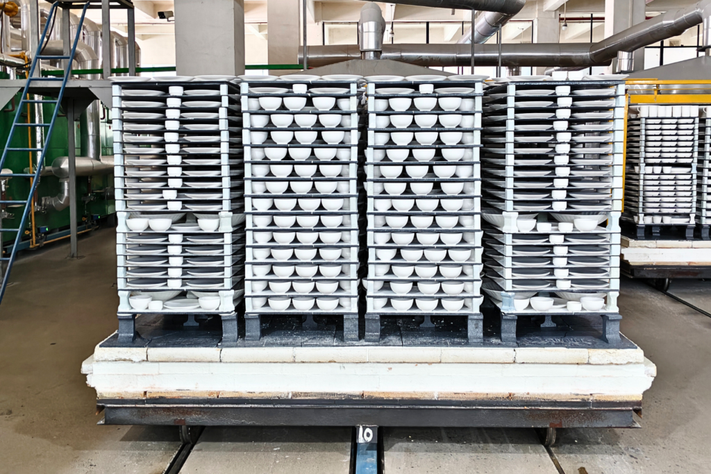 Shelf-and-block kiln furniture layout with ceramic bowls stacked on kiln shelves supported by mullite blocks.